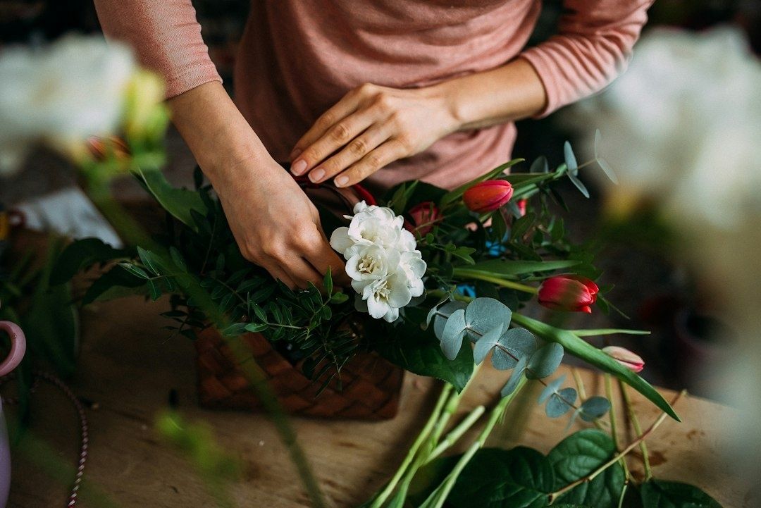 Händer formar en bukett med blommor och gröna stjälkar